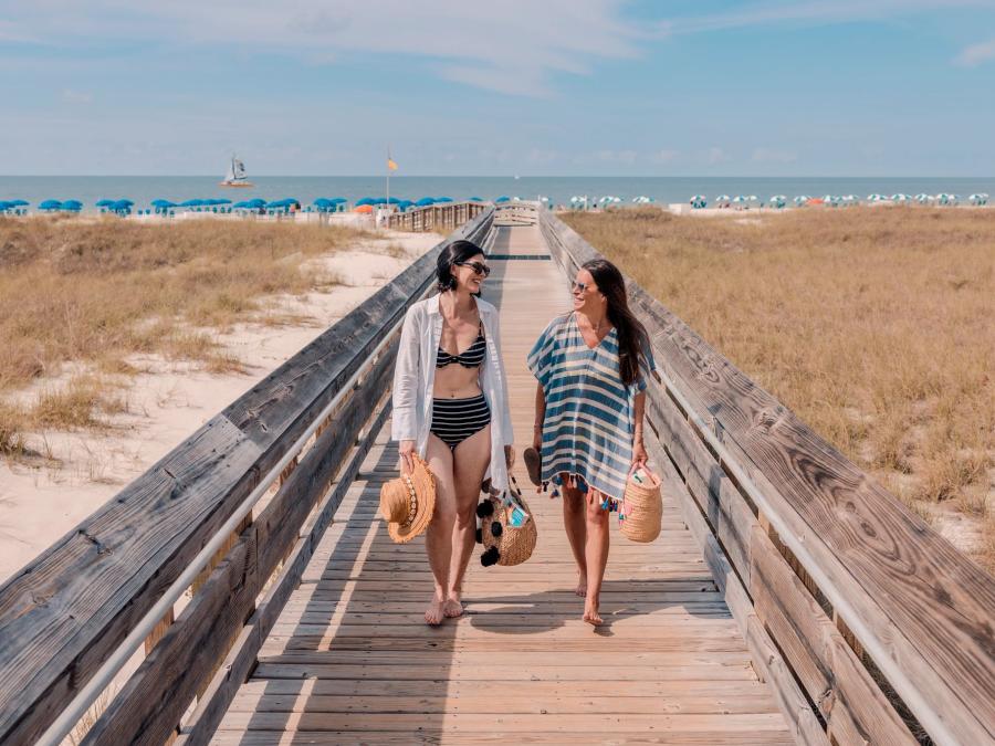 Two women walking on a boardwalk from the Gulf in Orange Beach