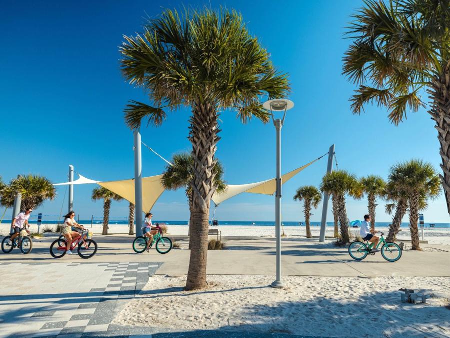 Friends riding bikes along the beach at Gulf Place in Gulf Shores